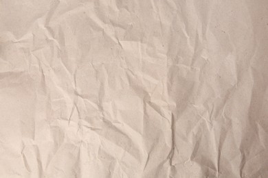 Sheet of crumpled light brown paper as background, top view