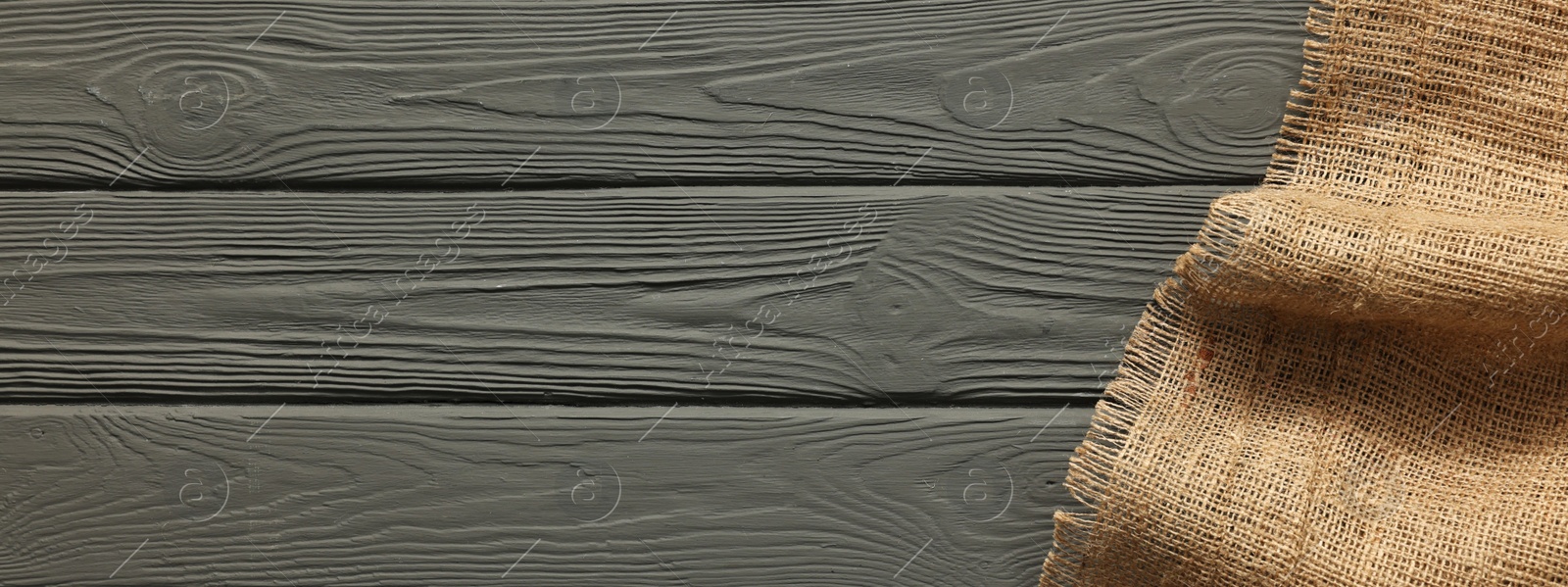 Photo of Burlap fabric on grey wooden table, top view. Space for text