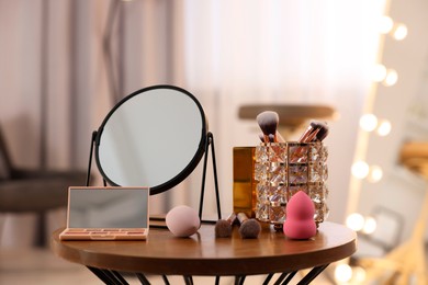 Different beauty products and mirror on wooden table in makeup room