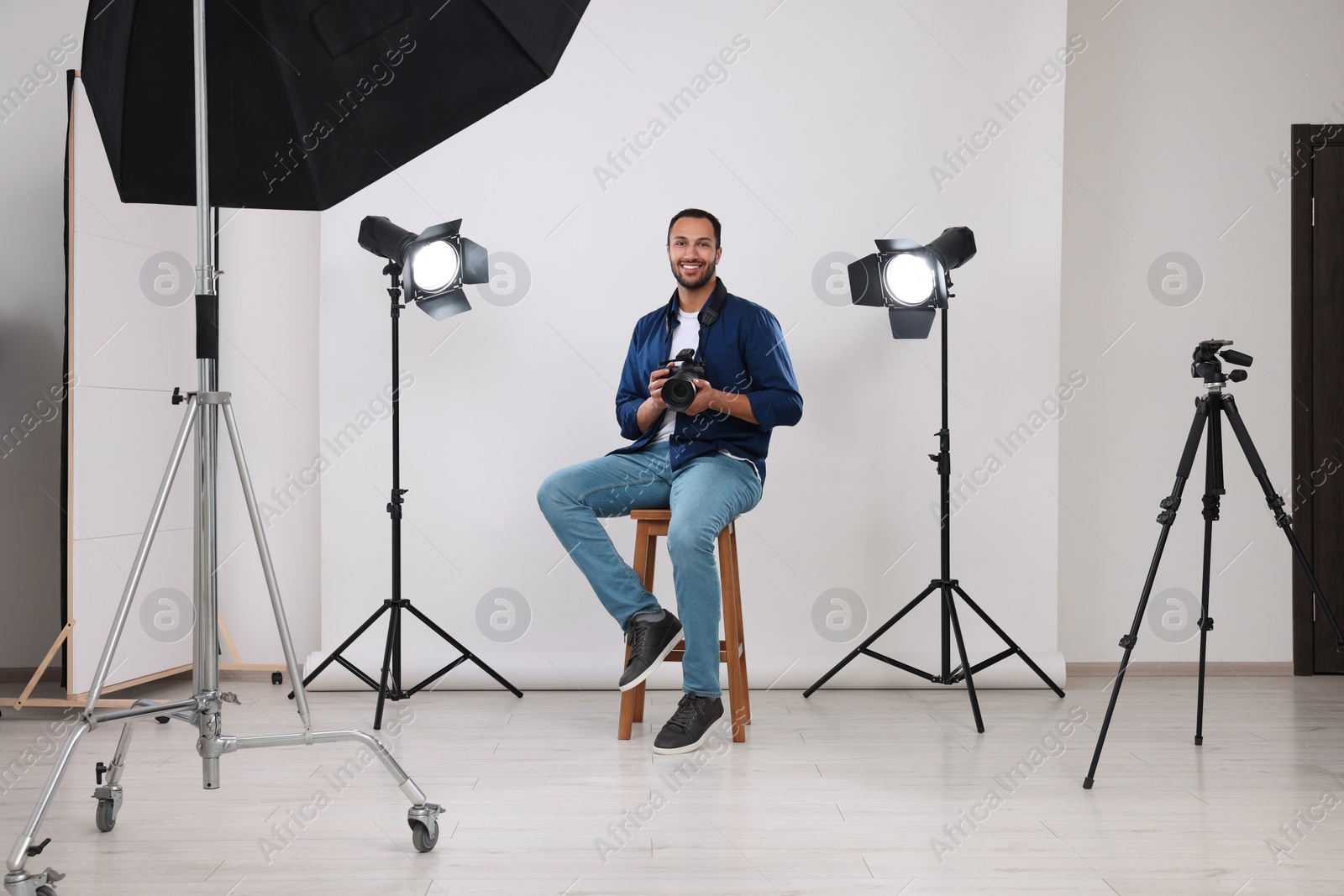 Photo of Young professional photographer with camera in modern photo studio