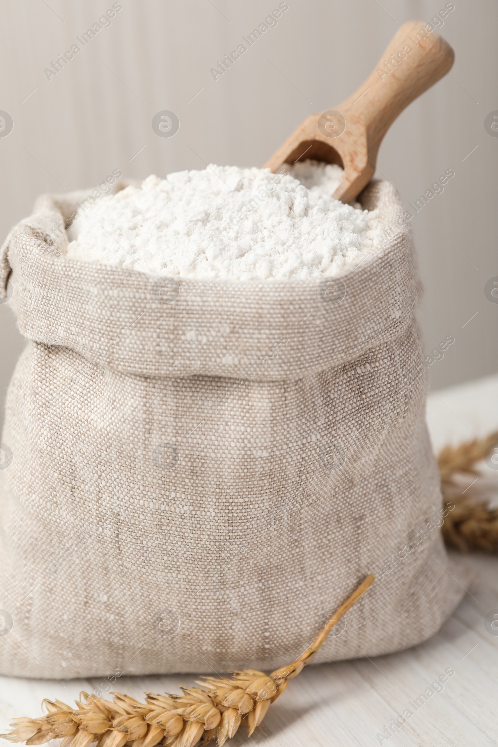 Photo of Wheat flour and spikelets on white table, closeup