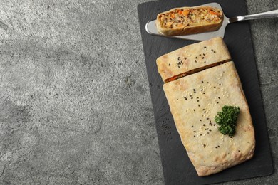 Photo of Delicious strudel with chicken and vegetables on grey textured table, flat lay. Space for text