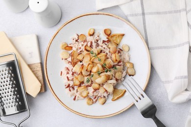 Plate with baked salsify roots, lemon, rice and fork on light grey table, flat lay