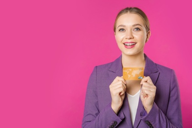Photo of Happy businesswoman with credit card and space for text on color background. Money transaction