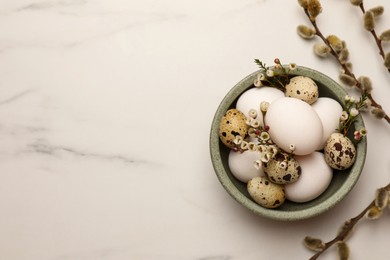 Easter eggs, flowers and pussy willow branches on white marble table, flat lay. Space for text