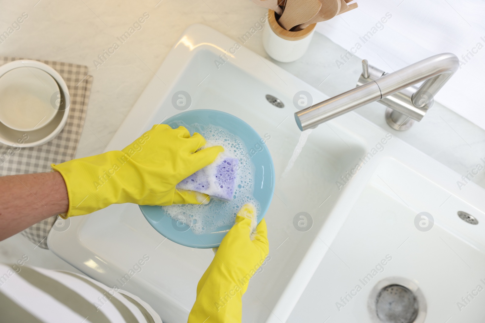 Photo of Man washing plate in kitchen sink, top view