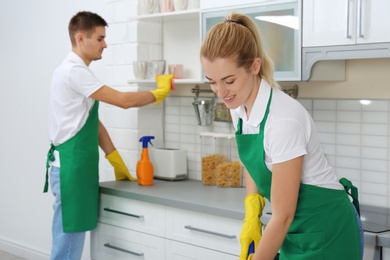 Team of janitors cleaning kitchen in house