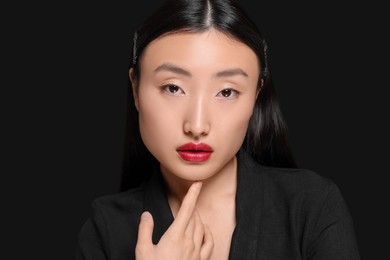 Portrait of beautiful young Asian woman on black background, space for text