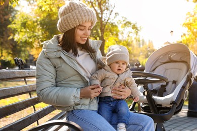 Photo of Happy mother with her baby son and stroller in park on autumn day