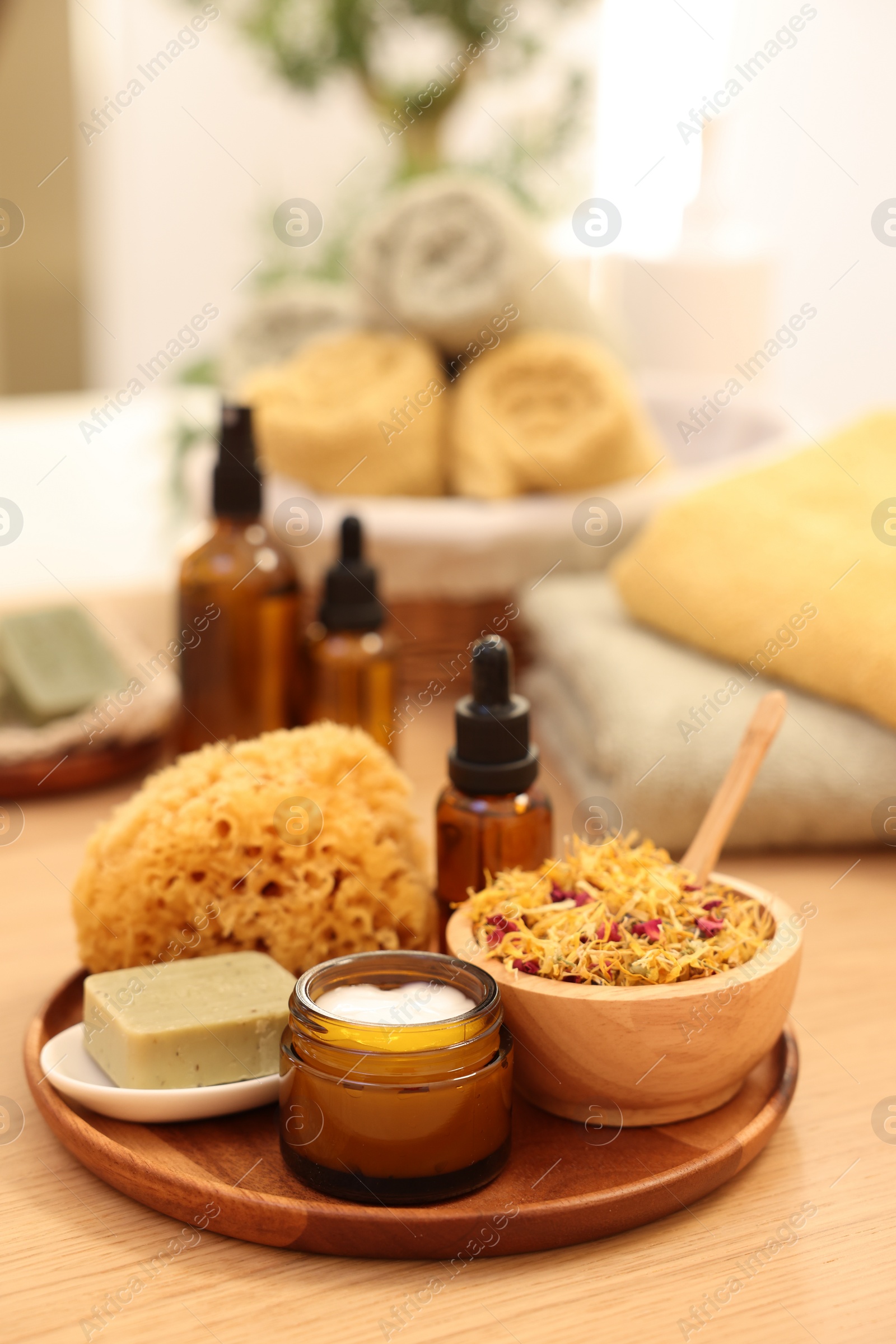 Photo of Dry flowers, loofah, soap bar, bottle of essential oil and jar with cream on wooden table indoors, space for text. Spa time