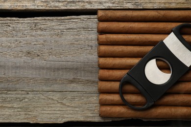 Cigars and guillotine cutter on wooden table, top view. Space for text