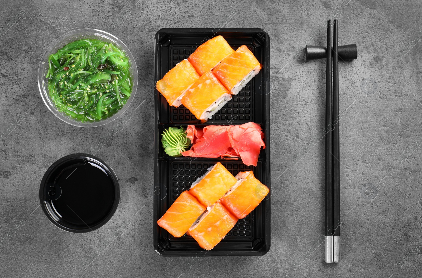 Photo of Tasty sushi rolls served on grey table, top view. Food delivery