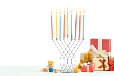 Hanukkah celebration. Menorah with colorful candles, dreidels and gift boxes on white background