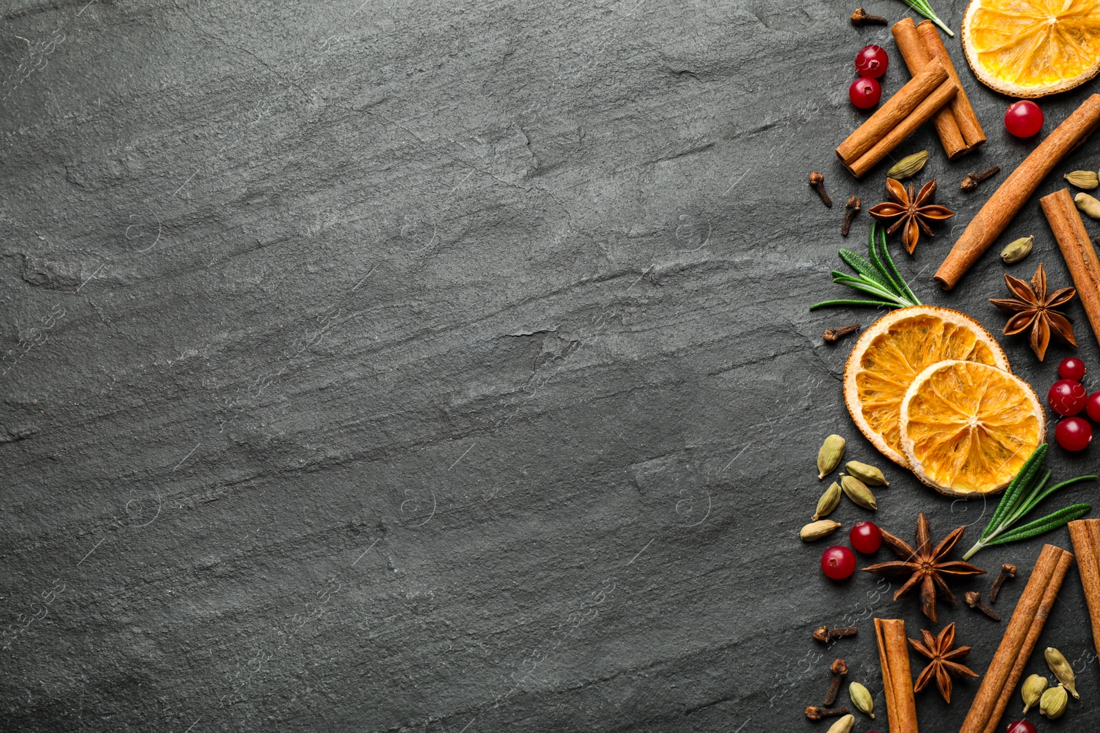 Photo of Different mulled wine ingredients on black slate table, flat lay. Space for text