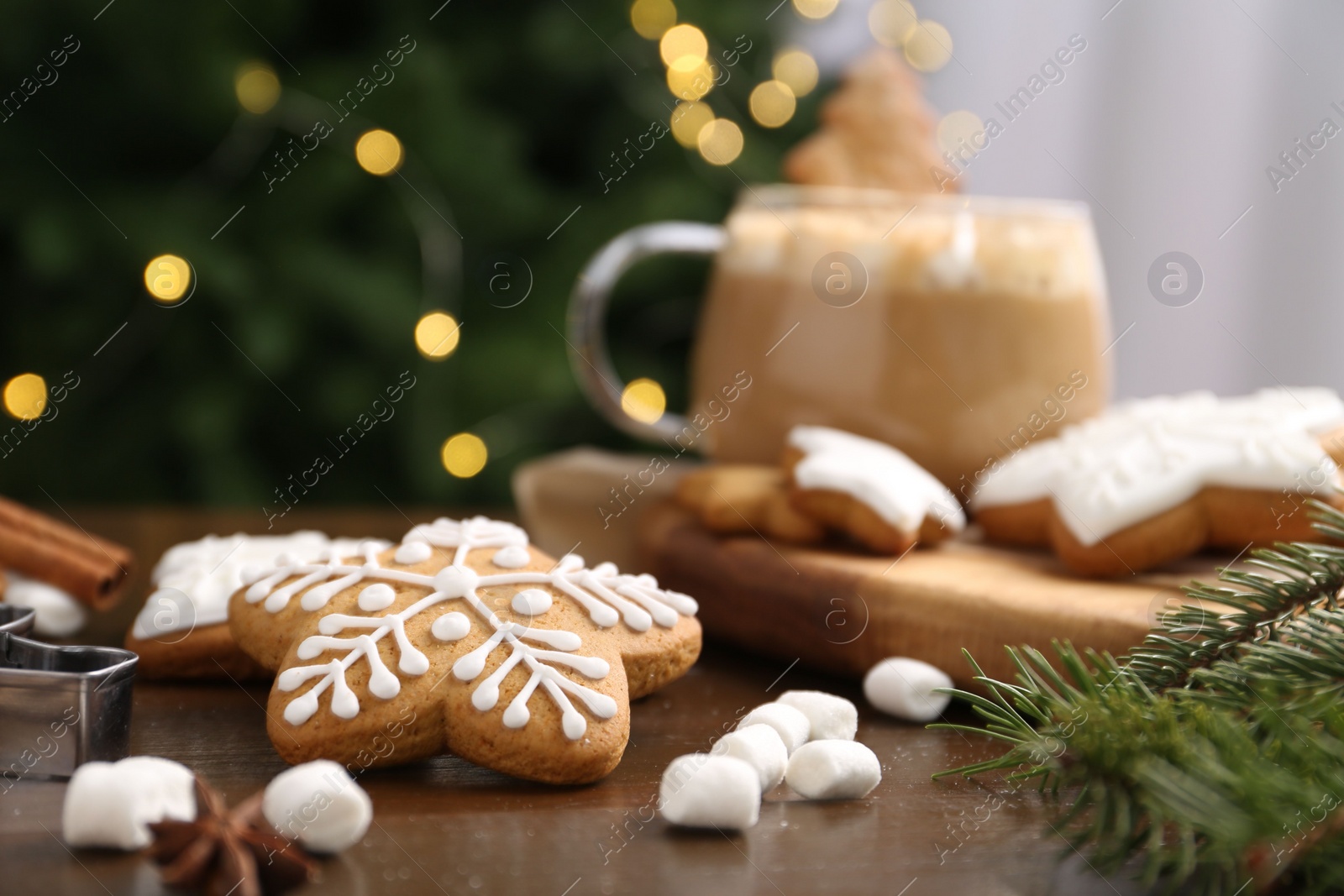 Photo of Decorated cookies on table against blurred Christmas lights, closeup