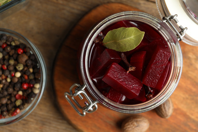 Delicious pickled beets and spices on wooden table, flat lay