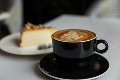 Cup of fresh coffee and dessert on table indoors