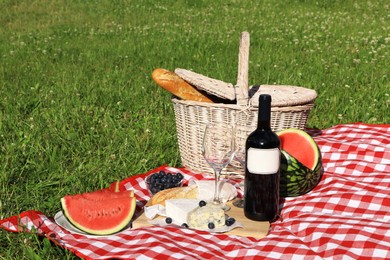 Photo of Picnic blanket with delicious food and wine outdoors on summer day