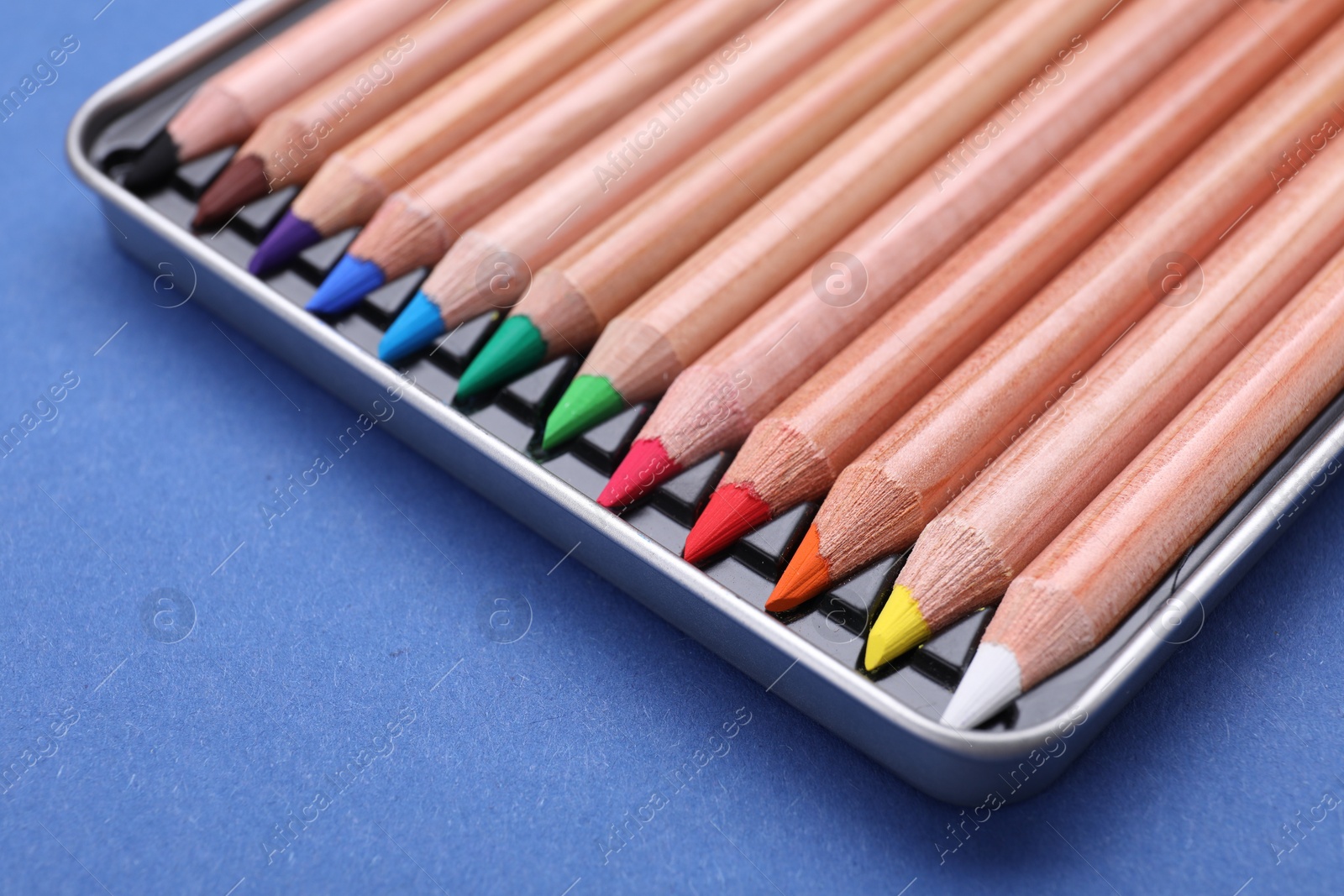 Photo of Colorful pastel pencils in box on blue background, closeup. Drawing supplies