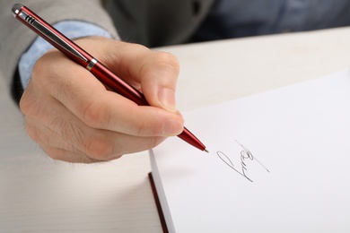 Writer signing autograph in book at table, closeup