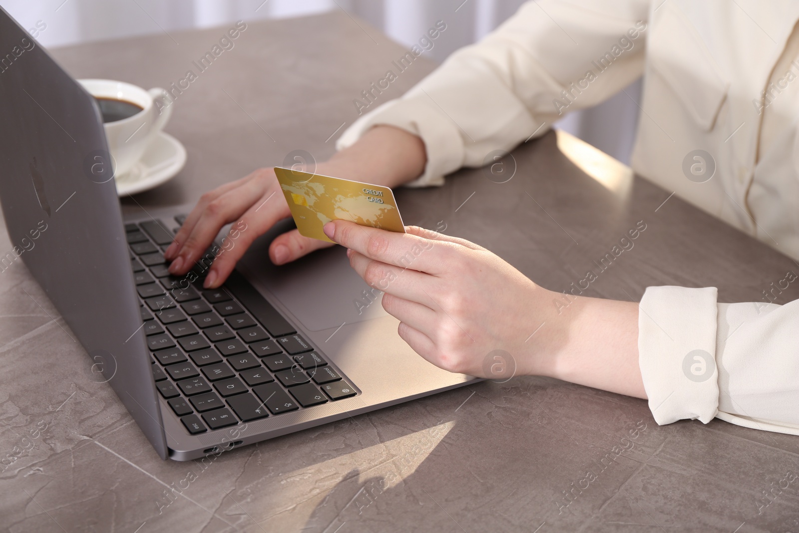 Photo of Online payment. Woman with laptop and credit card at grey table, closeup