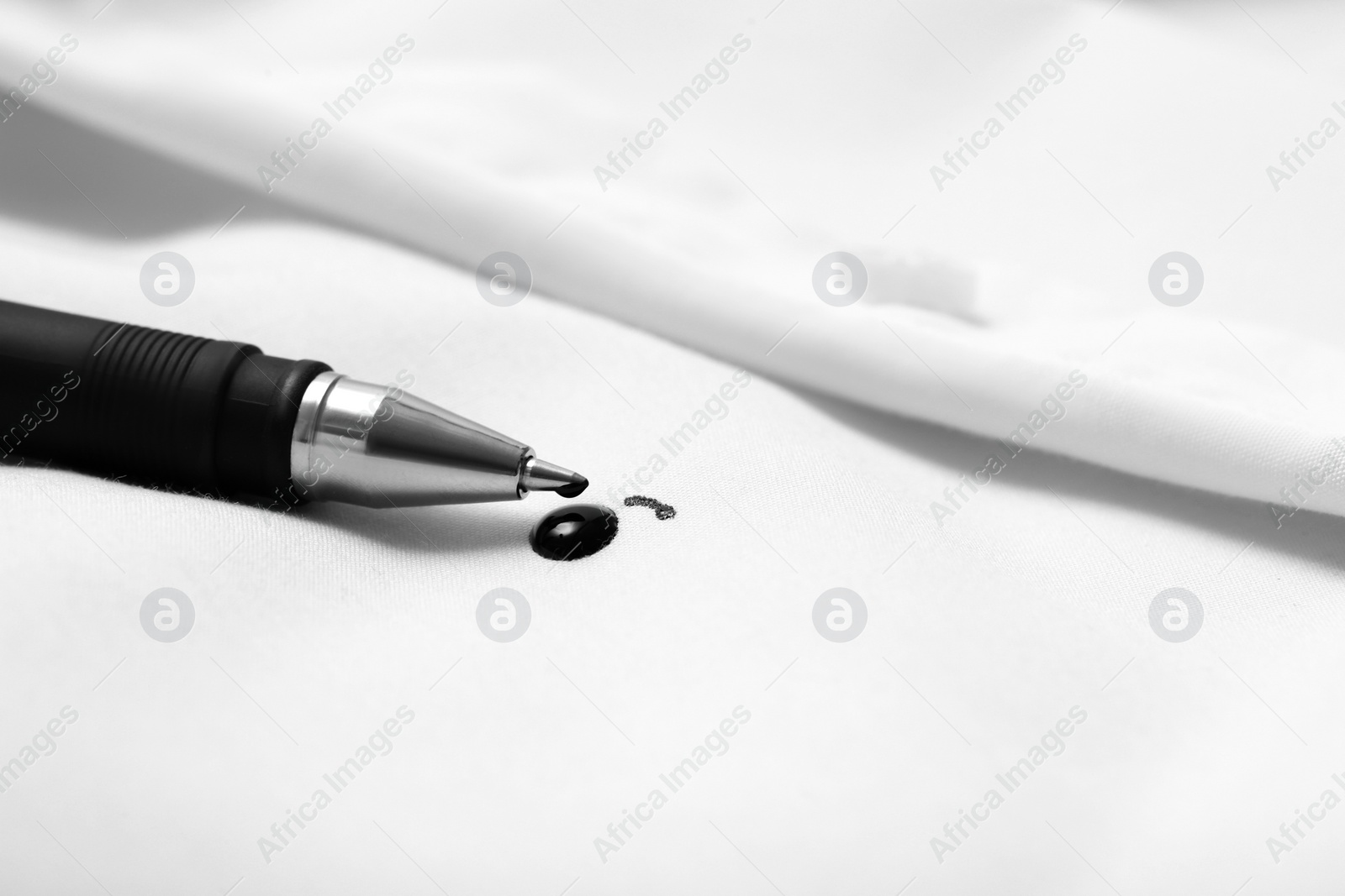 Photo of Pen and stain of black ink on white shirt, closeup. Space for text