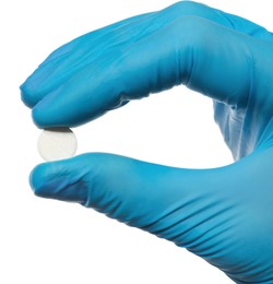Photo of Scientist in protective gloves holding pill on white background, closeup