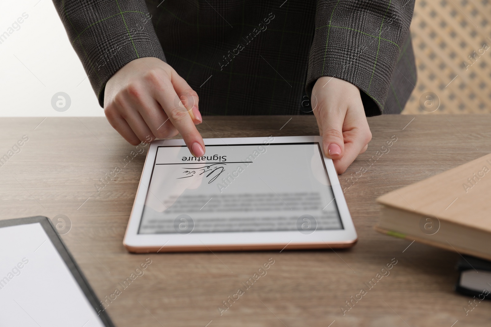 Image of Electronic signature. Woman using tablet at wooden table, closeup