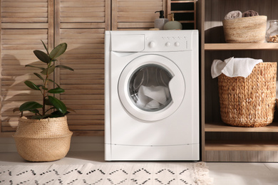 Photo of Modern washing machine and shelving unit in laundry room interior