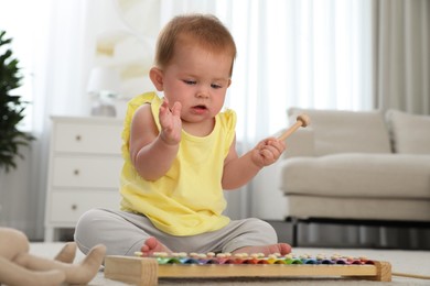 Photo of Cute little redhead baby playing with xylophone at home