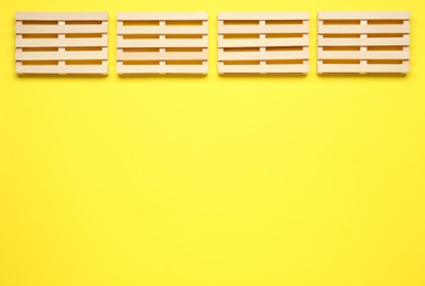 Photo of Wooden pallets on yellow background, flat lay. Space or text