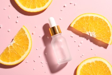 Bottle of cosmetic serum and orange slices on pink background, flat lay