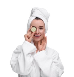 Photo of Beautiful woman in bathrobe covering eye with piece of cucumber on white background