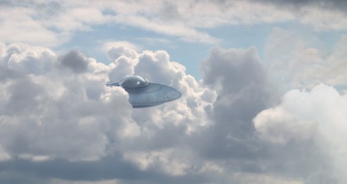 Image of UFO. Alien spaceship showing up from clouds in sky. Extraterrestrial visitors