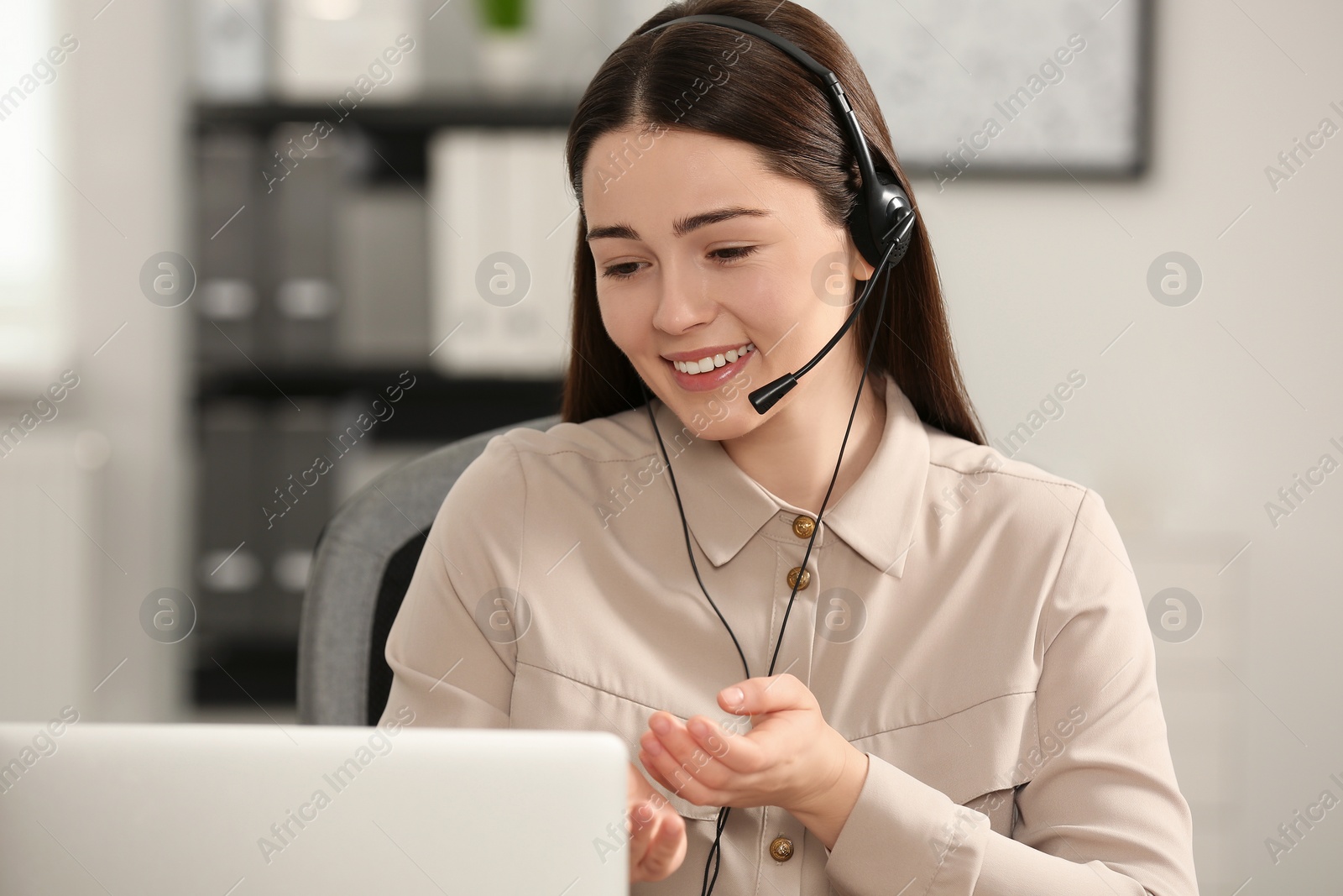 Photo of Hotline operator with headset working on laptop in office