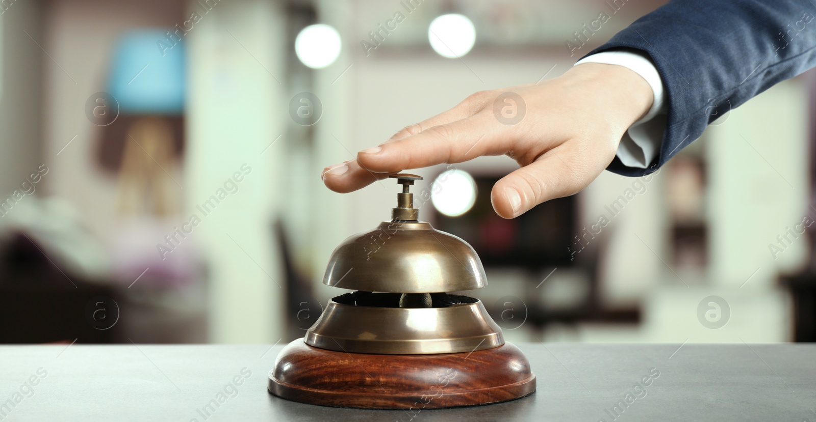 Image of Man ringing hotel service bell on blurred background, closeup. Banner design