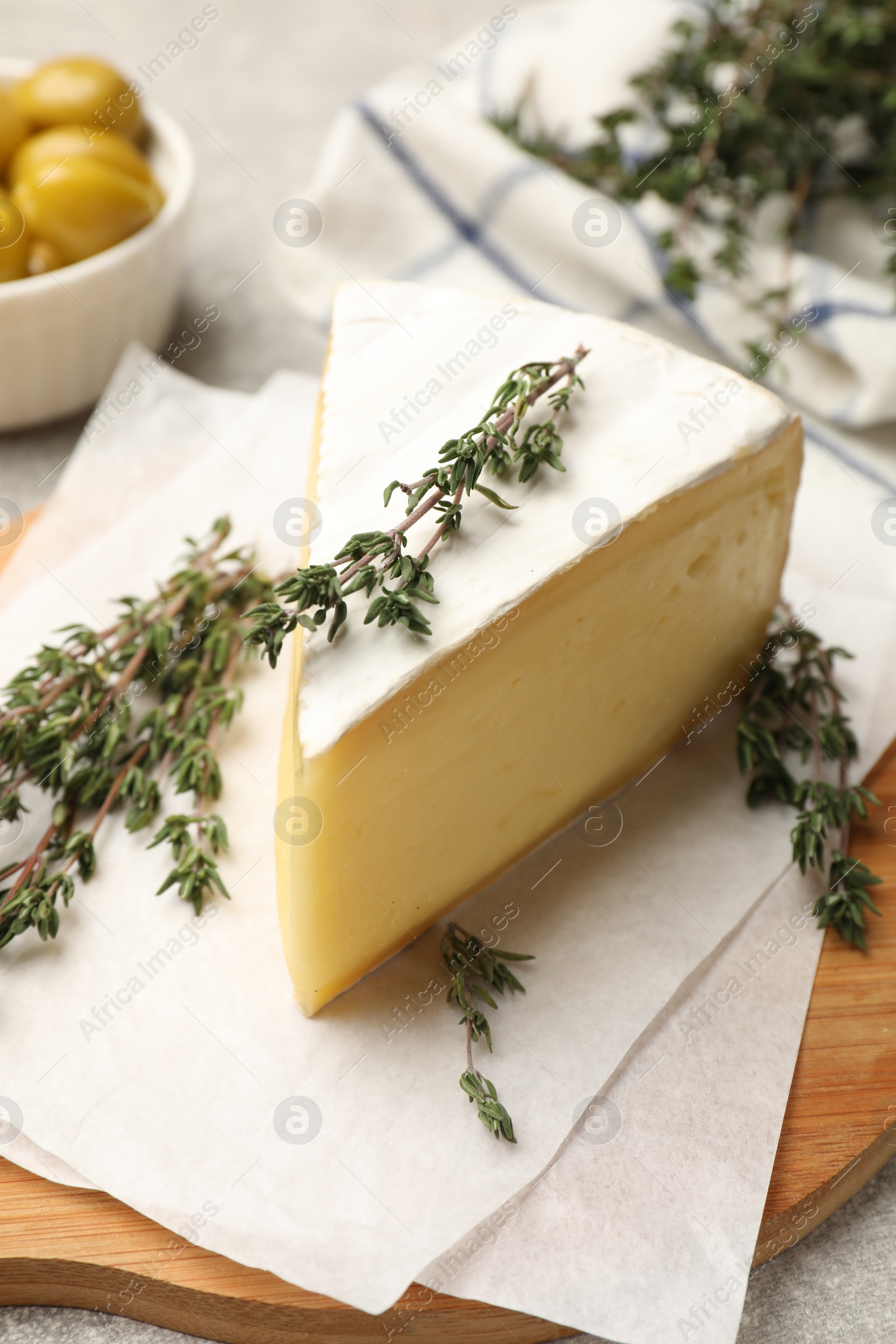 Photo of Piece of tasty camembert cheese and thyme on table, closeup