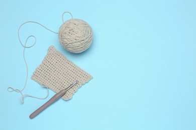 Photo of Clew of thread, knitting and crochet hook on light blue background, flat lay. Space for text