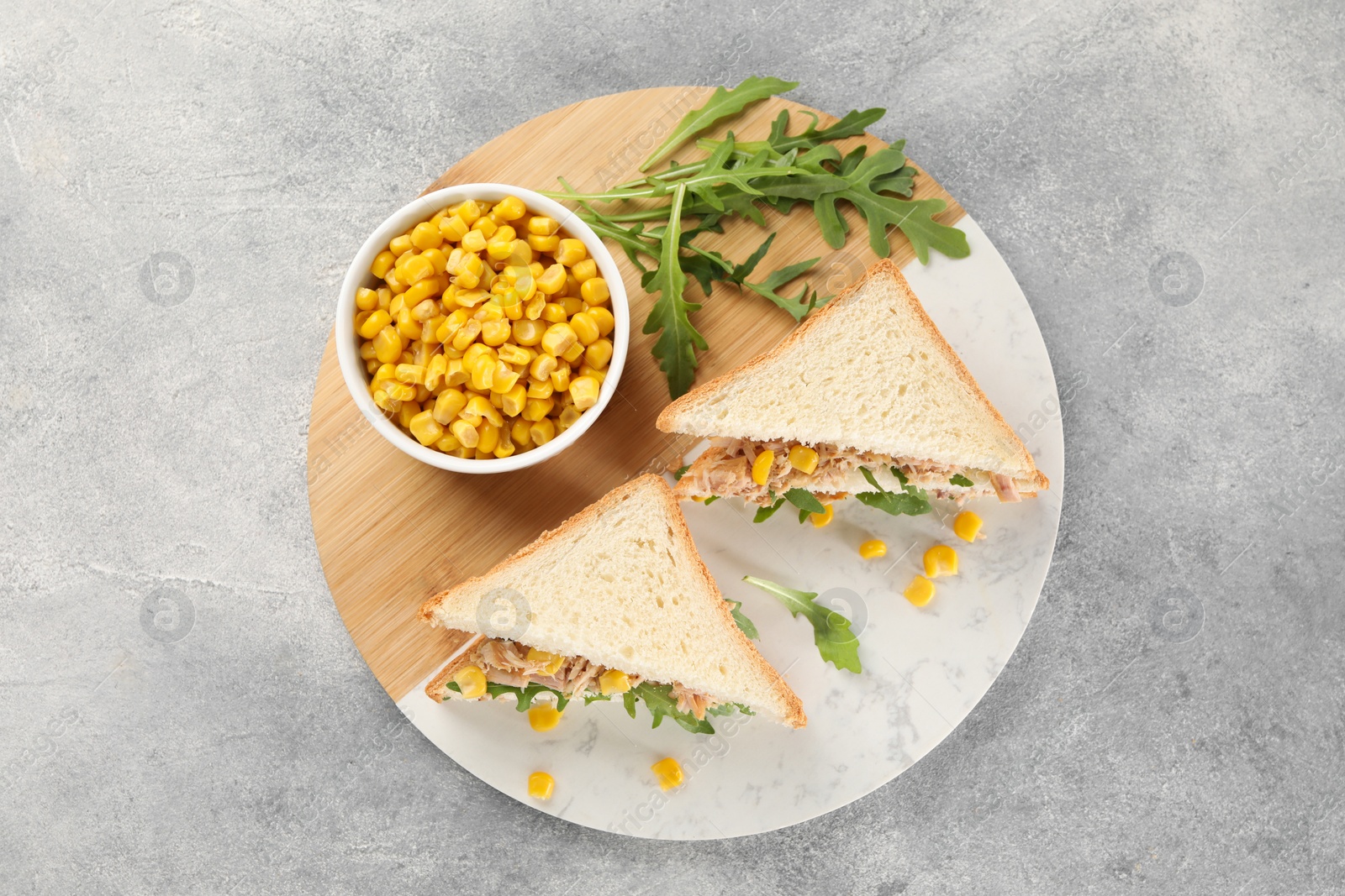 Photo of Delicious sandwiches with tuna, corn and greens on light grey table, top view