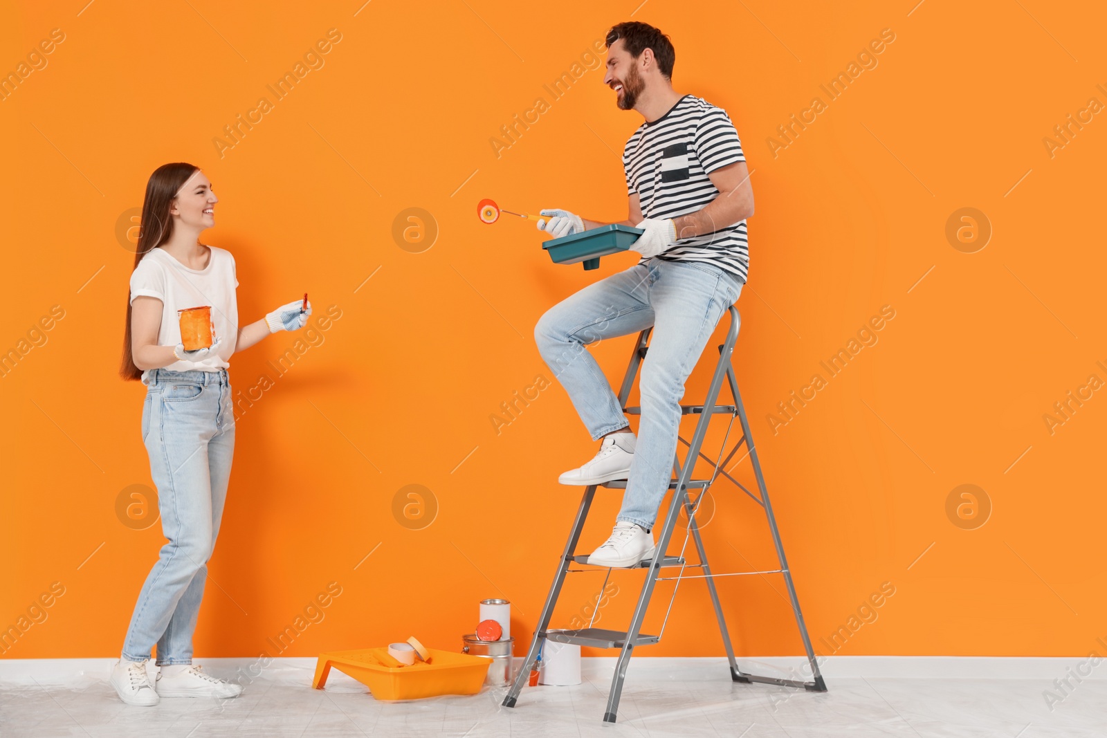 Photo of Designers with painting equipment near freshly painted wall indoors