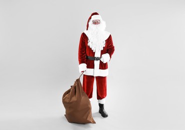 Photo of Full length portrait of Santa Claus with sack on light grey background