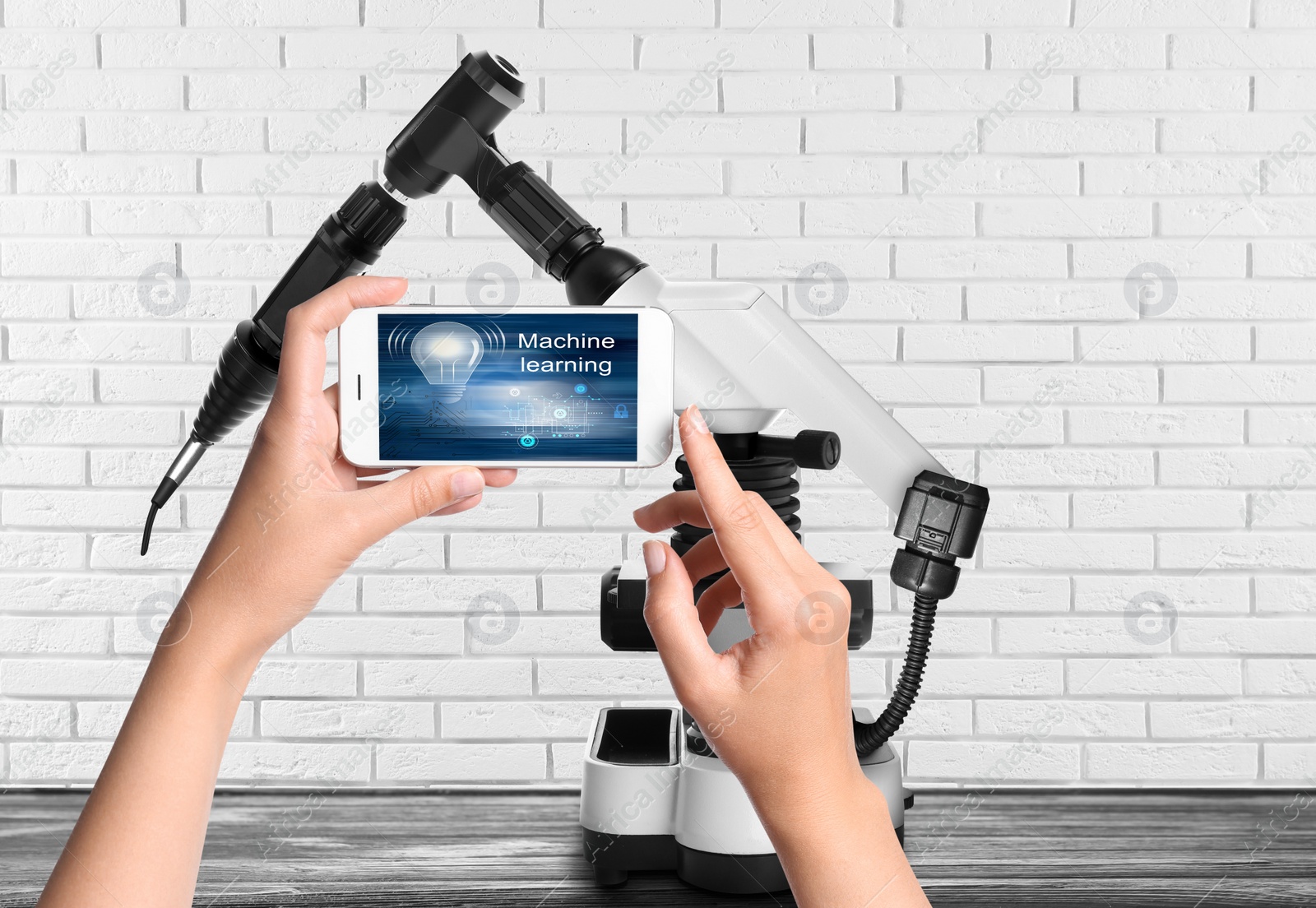 Image of Engineer controlling electronic laboratory robot manipulator with smartphone indoors, closeup. Machine learning