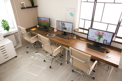 Photo of Stylish workplace interior with computers on tables