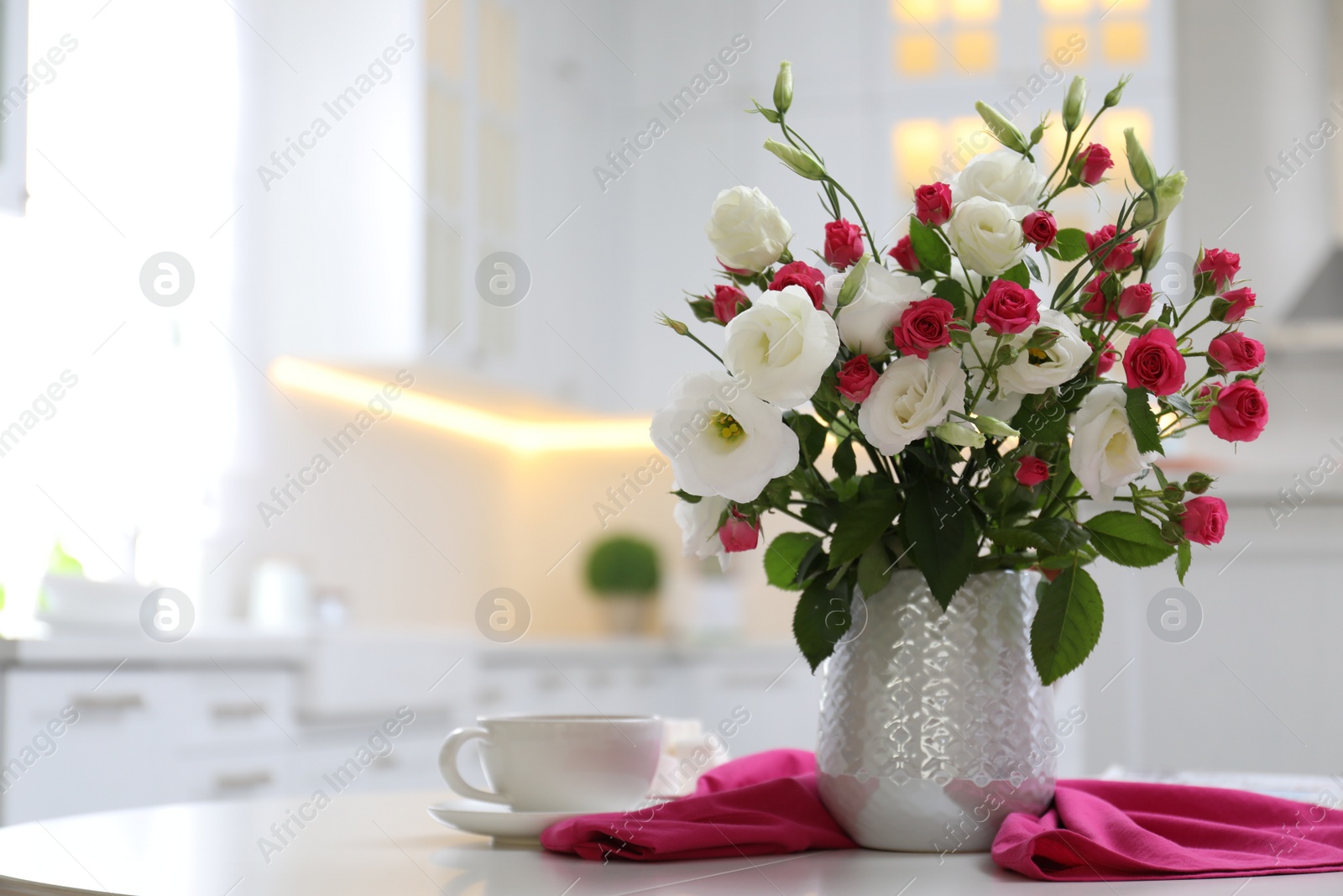 Photo of Vase with fresh flowers and cup on table in kitchen. Space for text