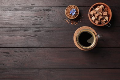 Photo of Glass cup of delicious chicory drink, granules, brown sugar and flower on wooden table, flat lay. Space for text