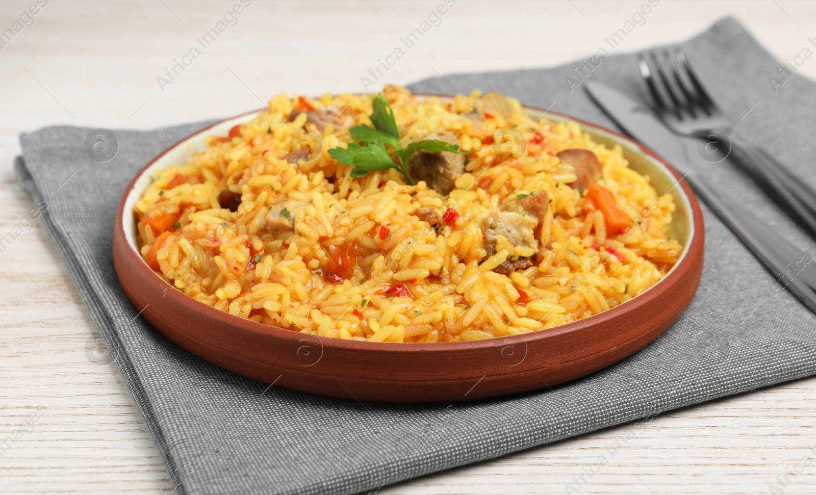 Photo of Delicious pilaf with meat served on white wooden table, closeup