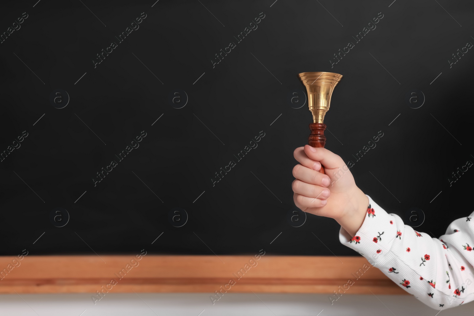 Photo of Pupil with school bell near black chalkboard, closeup. Space for text