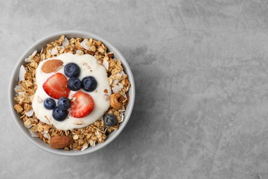Photo of Tasty granola, yogurt and fresh berries in bowl on light grey table, top view with space for text. Healthy breakfast