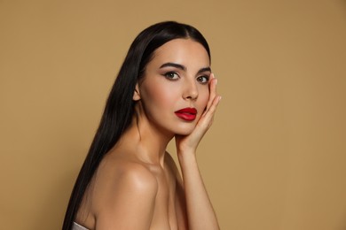 Photo of Portrait of young woman wearing beautiful red lipstick on beige background. Space for text
