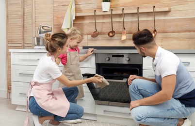 Photo of Happy family baking cookies in oven at home